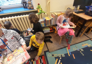 Dzieci wybierają i oglądają książki znajdujące się w bibliotece