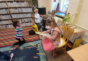 Dzieci wybierają i oglądają książki znajdujące się w bibliotece