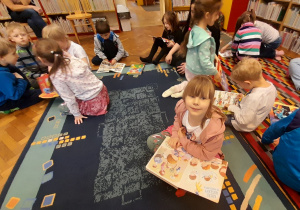 Dzieci wybierają i oglądają książki znajdujące się w bibliotece