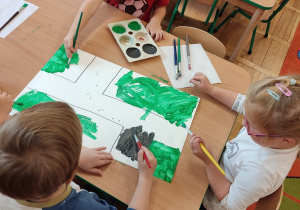 Dzieci malują farbami przy stoliku.