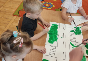 Dzieci malują farbami ulicę.
