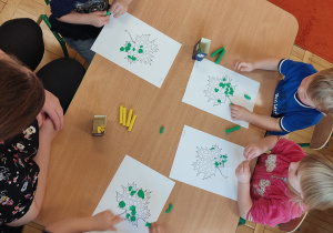 Dzieci wyklejają plasteliną liście.