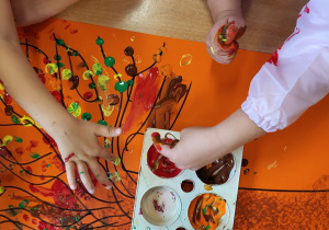 Dzieci malują paluszkami moczonymi w farbie.