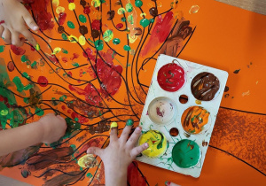 Dzieci malują jesienne drzewo farbą.