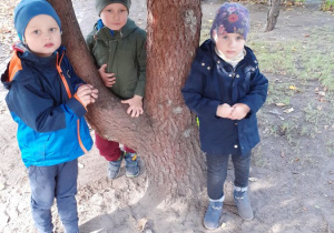 Dzieci podczas zabawy stoją przy drzewie