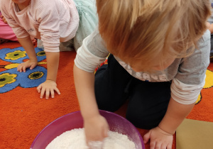 Chłopiec miesza mąkę i sól w misce.