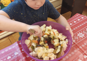 Chłopiec miesza sałatkę owocową.