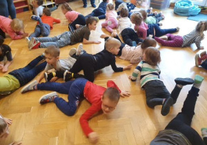 Dzieci uczestniczą w zabawie ruchowej: czołgają się po sali.