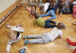 Dzieci uczestniczą w zabawie ruchowej: czołgają się po sali.
