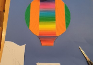 Na zdjęciu widać jak z kolorowych kartek naklejanych na arkuszu papieru powstaje balon.