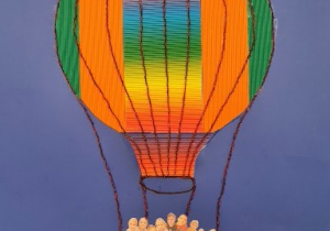Zdjęcie przedstawia lecący balon a w jego koszu widać dzieci.