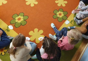 Dzieci siedzą na dywanie i opowiadają o swoich marzeniach.