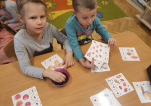 Dzieci trzymają w ręku karteczki z zabawami matematycznymi.