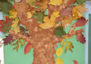 Na zdjęciu widać namalowane drzewo, ozdobine naturalnymi jesiennymi liśćmi