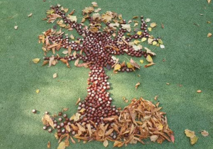 Na zdjęciu widać drzewo ułożone na boisku z darów jesieni