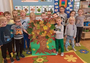 Dzieci prezentują swoją pracę plastyczną przedstawiającą drzewo jesienne