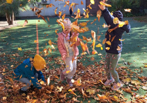 Dzieci podrzucają jesienne liście