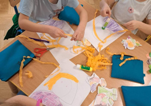 Na zdjęciu dzieci wyklejają z kolorowej krepiny i papieru portret "Pani Jesieni"
