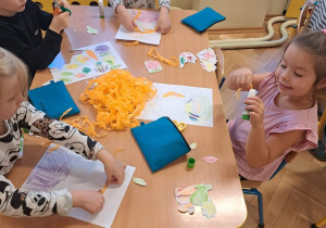 Na zdjęciu dzieci wyklejają z kolorowej krepiny i papieru portret "Pani Jesieni"