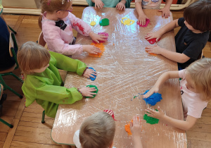 Dzieci klepią farbą po stoliku.