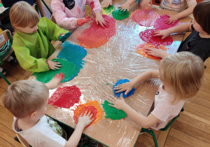 Dzieci malują farbą za pomocą rąk.