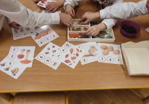 Dzieci przyczepiają klamerkę przy cyfrach odpowiadających jesiennym elementom na ilustracji. Zabawy matematyczne.