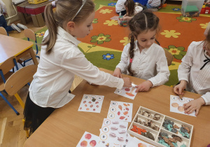 Dzieci przyczepiają klamerkę przy cyfrach odpowiadających jesiennym elementom na ilustracji. Zabawy matematyczne.