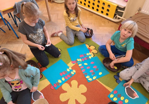 Dzieci układają rytmy z papierowych kolorowych liści.