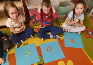 Dzieci z drucików układają kształt pisanej literki e