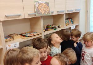 Dzieci zbierają się pod ilustracja legowiska.