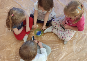 Dzieci mieszają farby w misce.
