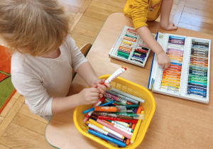 Dzieci wybierają kolory pasteli potrzebne do wykonania pracy.