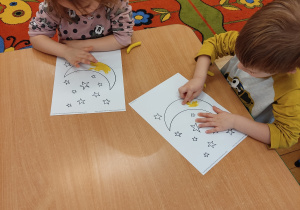Dzieci wyklejają księżyc i gwiazdy.