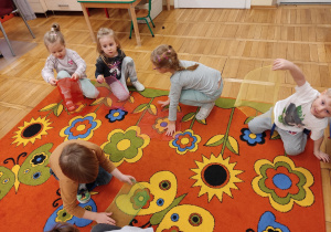 Dzieci tańczą na dywanie z chustkami.