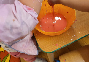 Dzieci dodają kolorowej farby do masy.