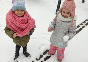 Dziewczynki bawią się na śniegu.