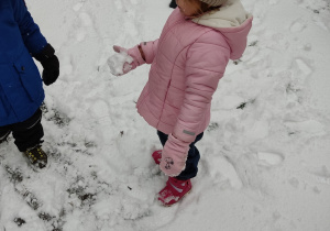 Dziewczynka robi kulkę ze śniegu.