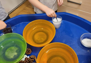 Dzieci mieszają różne substancje z wodą.