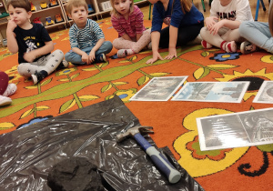 Dzieci na dywanie obserwują węgiel.