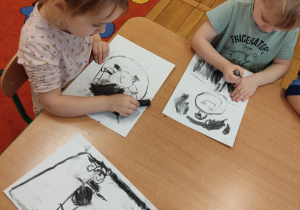 Dzieci rysują węglem.