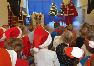 Św. Mikołaj rozdaje dzieciom prezenty.
