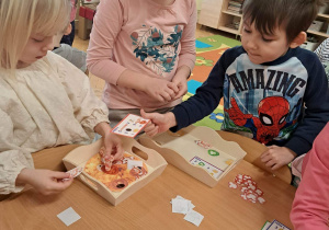 Dzieci dekorują pizzę.