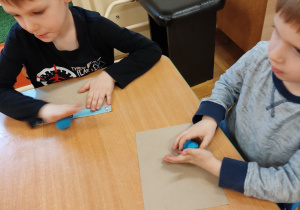 Dzieci bawią się plasteliną przy stoliku.