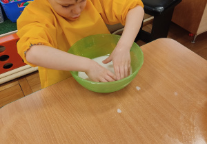 Chłopiec miesza wodę i mąkę ziemniaczaną.