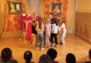 Dziewczynki tańczą w kole z królową.