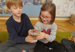 Dzieci przekazują sobie szklankę wypełnioną wodą