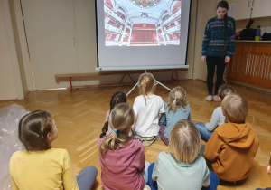 Na zdjęciu dzieci oglądają prezentację na temat opery