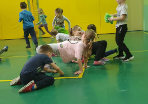 Na zdjęciu dzieci na sali gimnastycznej biorą udział w zajęciach sportowych