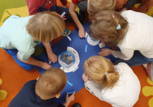 Na zdjęciu dzieci układają puzzle i zaznaczają, które zwierzęta mieszkają na Arktyce a które na Antarktydzie