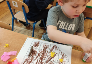 Chłopiec przykleja kolorowe kuleczki.